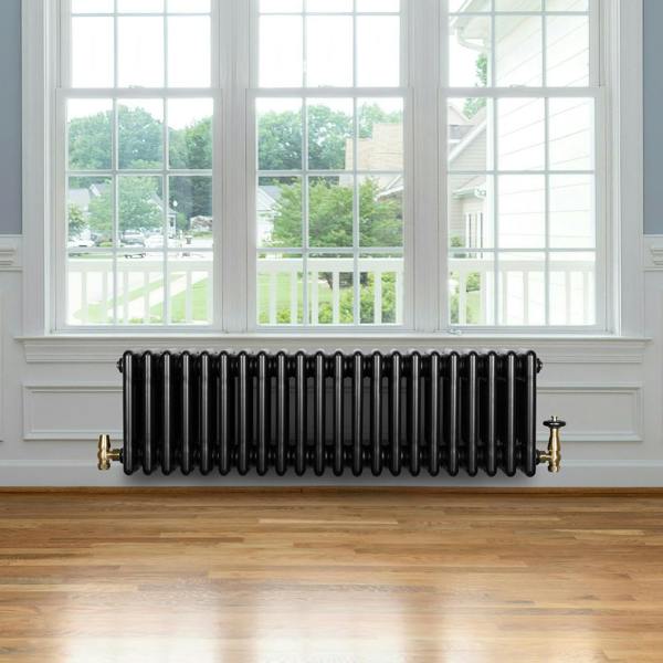 Traditional black 4 column radiator, 300 x 1010mm, featuring a sleek design with polished brass valves, set against a bright window backdrop