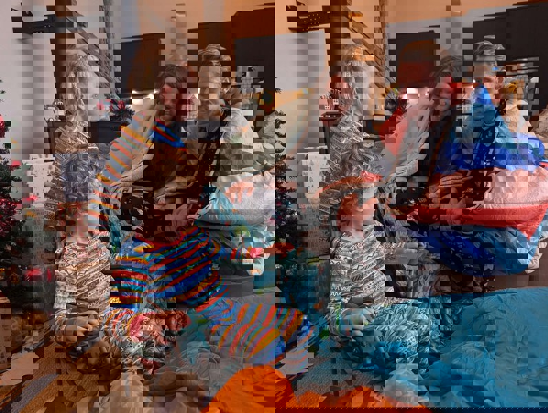 Family around the Christmas tree opening gifts, one being the Compact kids chair with design by Olpro.