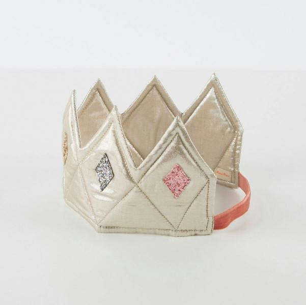 A high-angle studio product shot of the gold lamé fabric crown showing the soft padded interior structure and the smooth pink velvet elastic strap.
