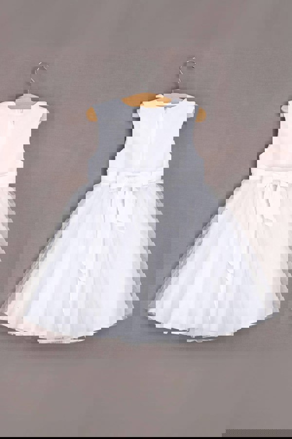 White dress with a bow on a hanger against a gray background