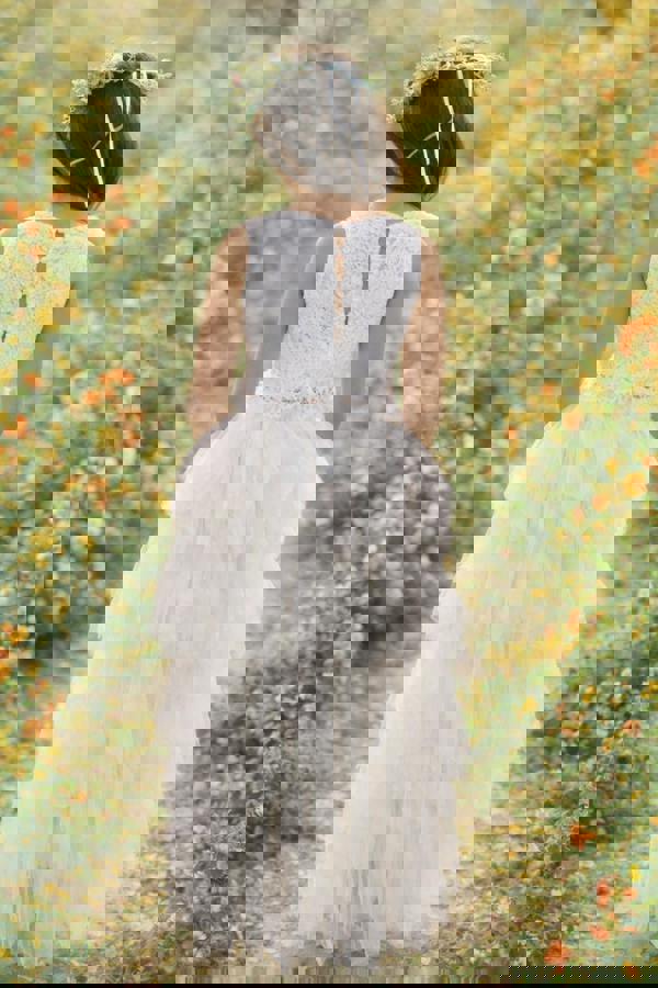 girl in a white lace dress standing in a field of flowers