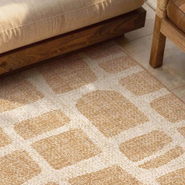 Patterned beige rug on a wooden floor with a sofa and chair in the background