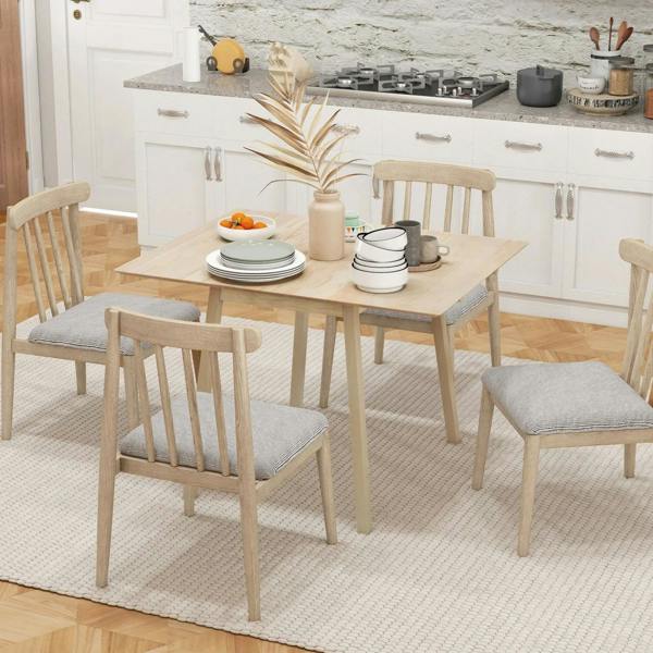 Natural wood drop-leaf dining table set with plates and chairs in a kitchen