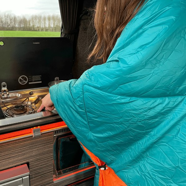 A woman stays cosy inside her OLPRO Reversible Blanko whilst she cleans her campervan