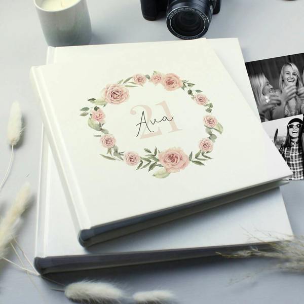 A square cream photo album printed with a pink watercolor rose wreath, the name Ava, and a faint number 21 on the cover.