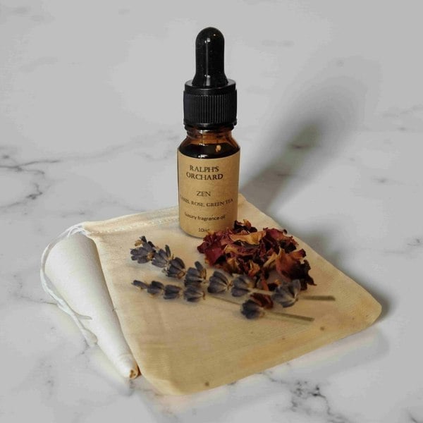 Bottle of 'Zen' essential oil by Ralphs Orchard on a wooden board with dried flowers on a marble background