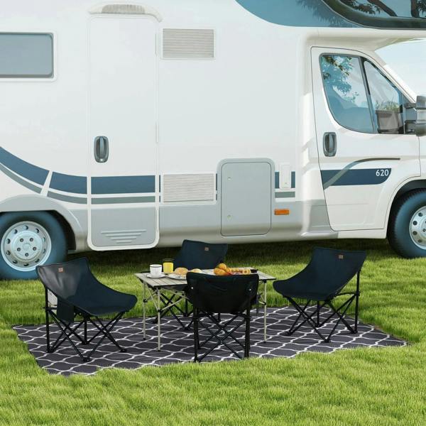 Black folding camping chairs with low metal legs and padded seats on outdoor mat