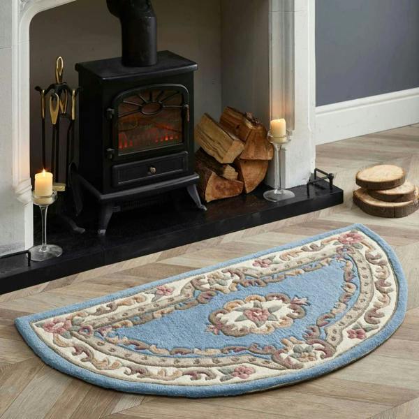 Decorative half-circle rug in front of a lit fireplace with wood and candles.