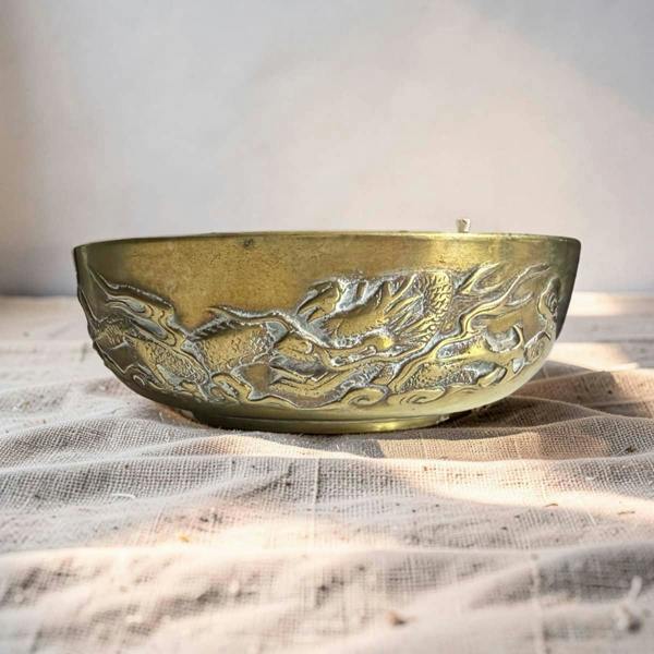 Decorative brass bowl with embossed design on a textured surface