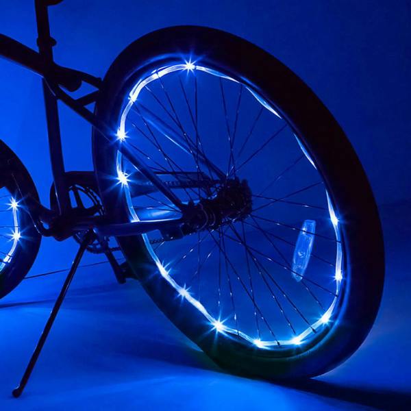 A bicycle wheel illuminated in the dark with a vibrant strip of bright blue-white LED lights wrapped around the inside of the rim.
