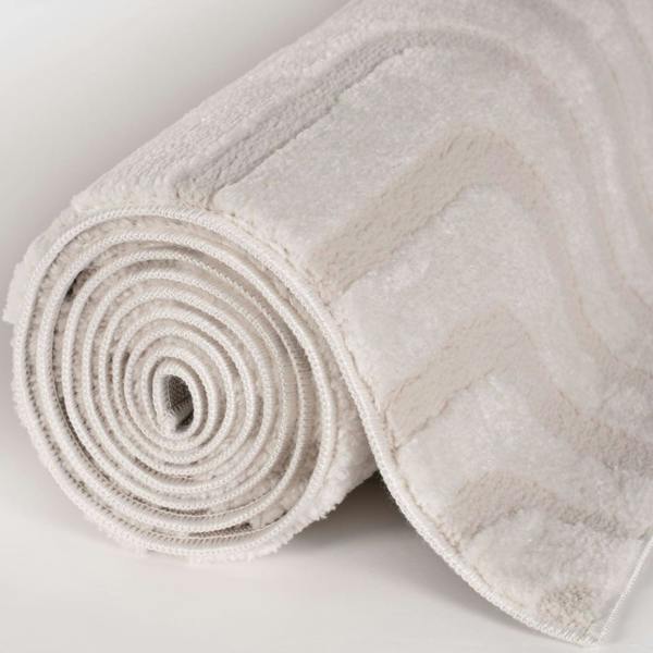 Rolled-up beige bath mat on a light gray background