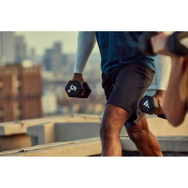 Person exercising with 5kg adidas dumbbells on a rooftop with cityscape in the background