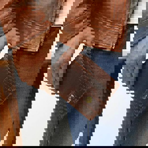 Person holding a brown leather wallet with a blurred background