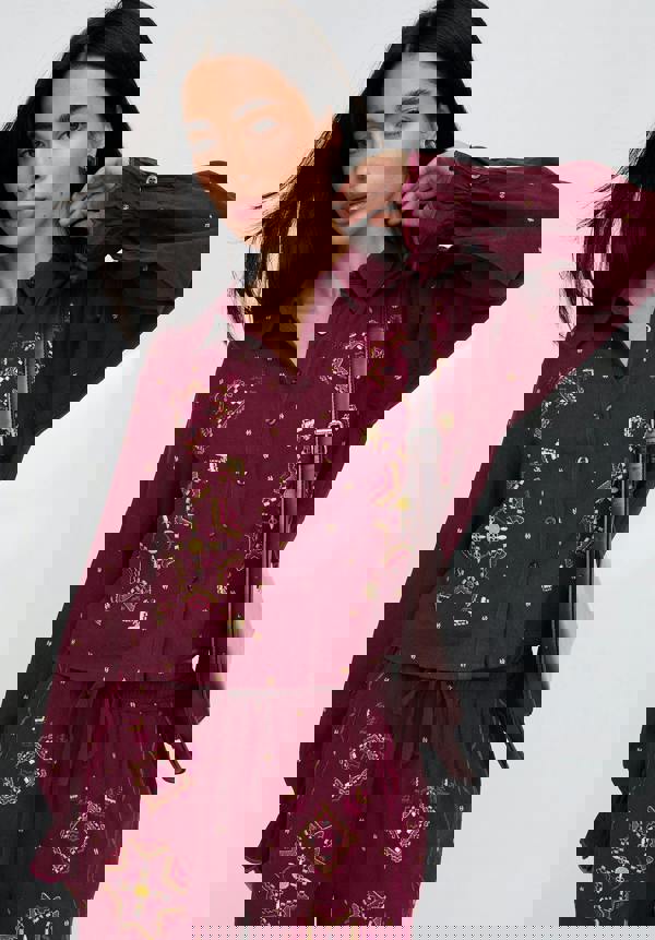 Woman wearing a burgundy embroidered outfit with a white background