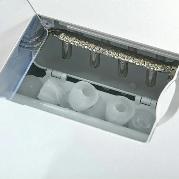 Open ice bin inside a silver ice maker with molded ice cubes