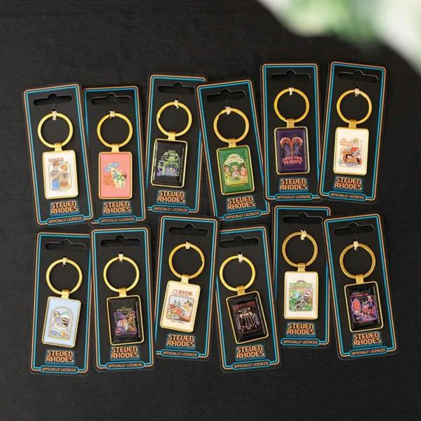 Set of gold keychains with square illustrated charms on Steven Rhodes retail cards.