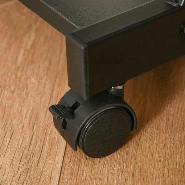 Close-up of black locking caster wheel under the edge of the desk