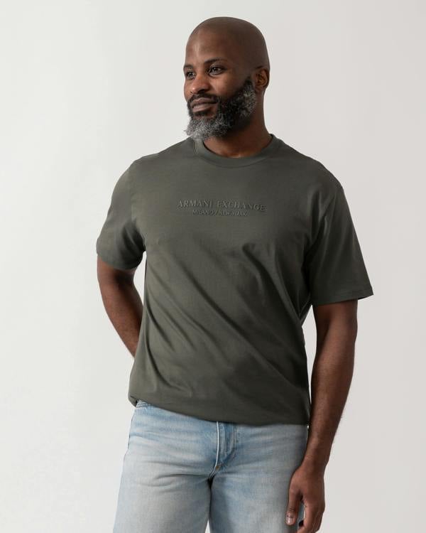 Model wearing an Armani Exchange Mens T-Shirt with Tonal Milano/New York Logo in Chimera