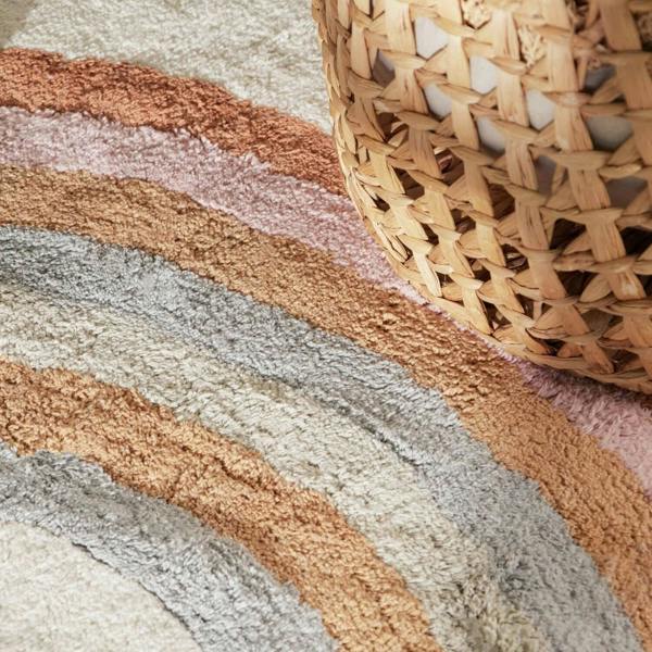 Close-up of a textured rug with wicker basket on a striped pattern