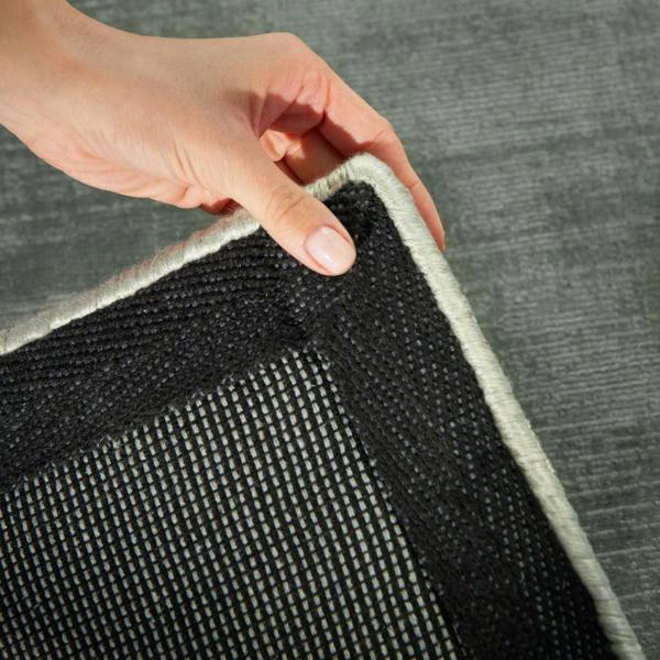 Person holding a corner of a black and gray rug