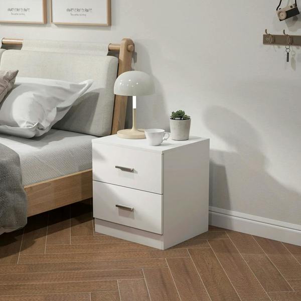 White bedside table with two drawers and metal bar handles near a bed