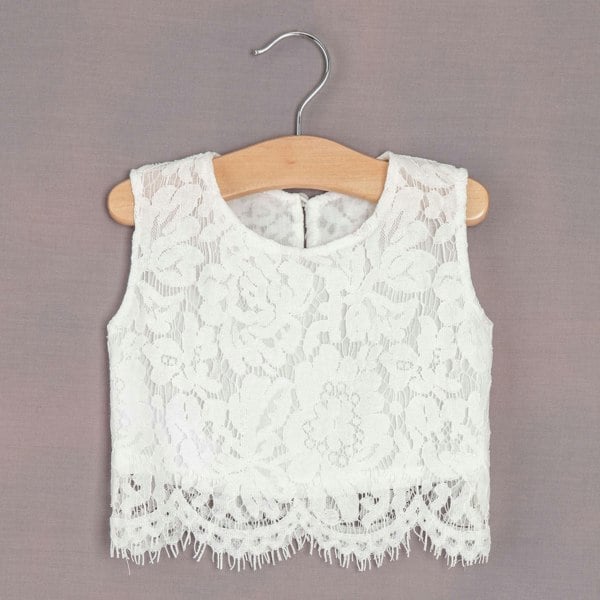 White lace top on a wooden hanger against a gray background