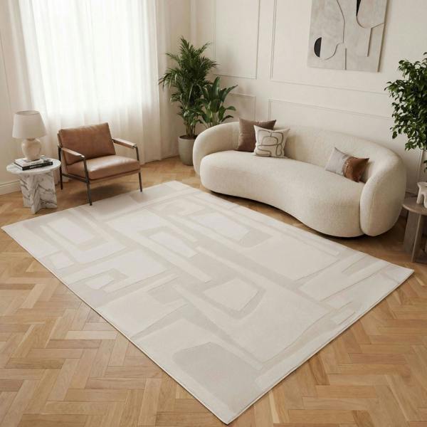 Modern living room with a large white rug, beige sofa, and wooden floor.