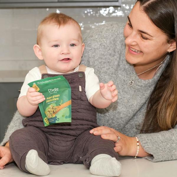 Baby holding packet of more toddler meals for dinner with mother