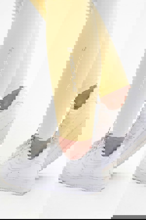 Ankle detail on the women's yellow leggings. The Discipline Logo sits on the side of the lower leg.