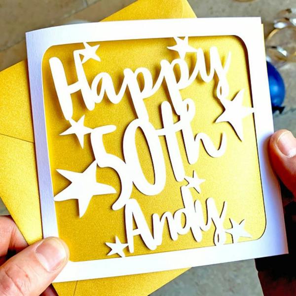 Personalised papercut 50th birthday card with the name Andy and stars against a shimmering gold paper insert