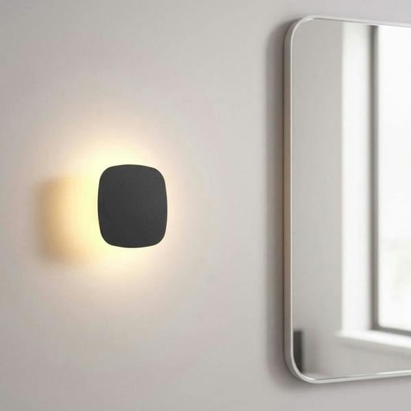 black vanity wall light mounted next to a bathroom mirror on the wall 