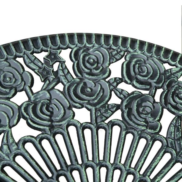 Close-up of antique green cast aluminum floral pattern tabletop surface.