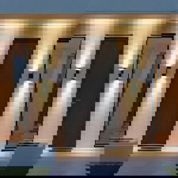 black outdoor up down light mounted either side of the front door on the wall of a modern home 