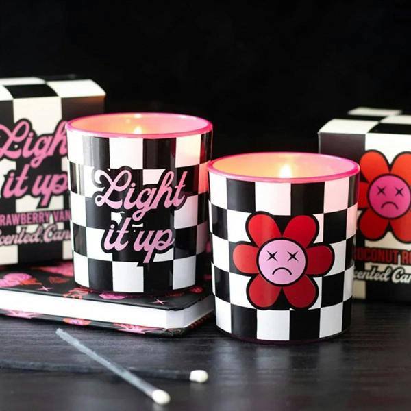 Two black-and-white checkered scented candle jars with pink wax tops