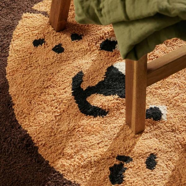 Round brown rug with black paw prints on a brown floor.