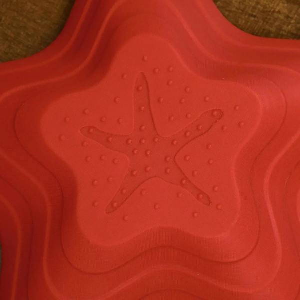 Red starfish stepping stone close-up with raised textured grip pattern.