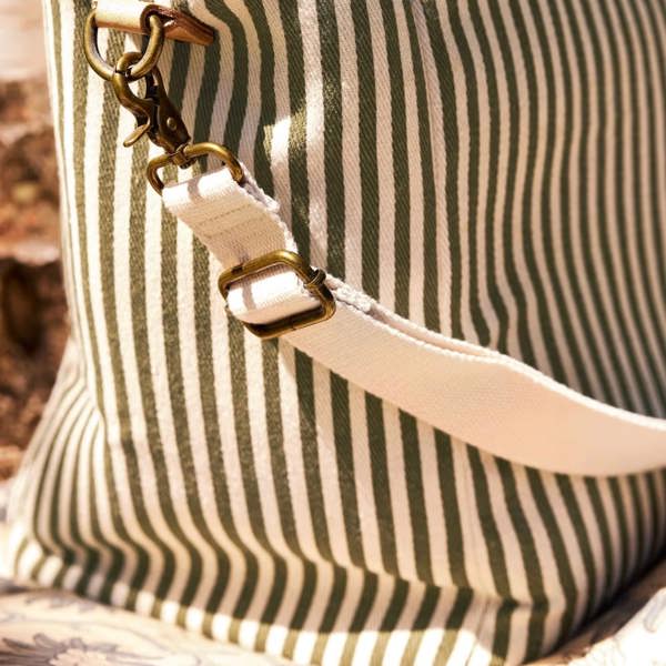 Detail of the adjustable canvas shoulder strap with antique brass clips.