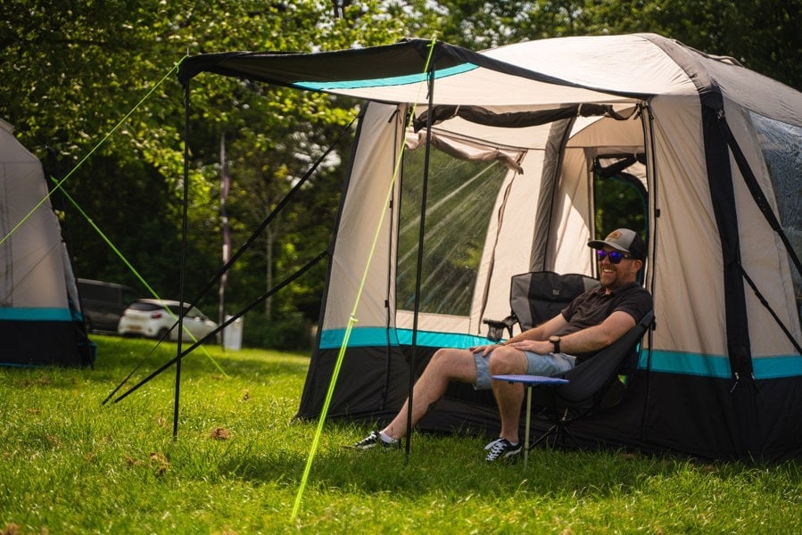 A man sits outside his OLPRO Snug Inflatable campervan Awning, He is sitting on a lightweight camping chair