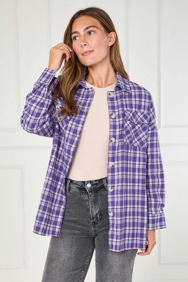 Woman wearing a purple plaid shirt over a beige top and gray jeans against a white background