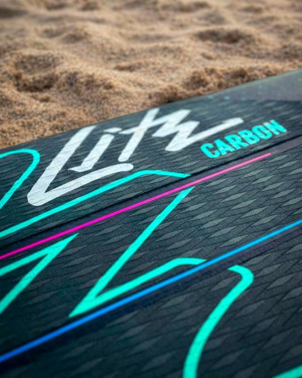 Close-up of a black paddleboard deck with colorful graphics and the word 'Carbon