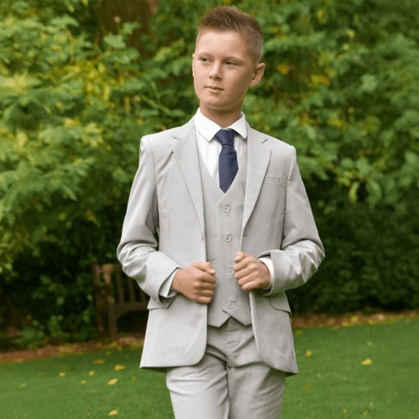 boy in a garden wearing a stone coloured 5 Piece Suit from uk flower girl boutique 