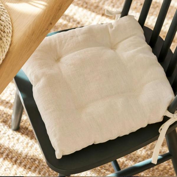 A Chalk white 100% linen seat pad tied to a black spindle dining chair.