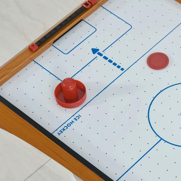 Angled view of wooden tabletop air hockey table with red pucks and blue lines