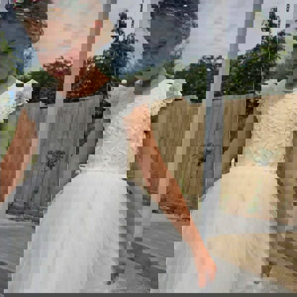 Gril in a garden wearing. flower girl dress