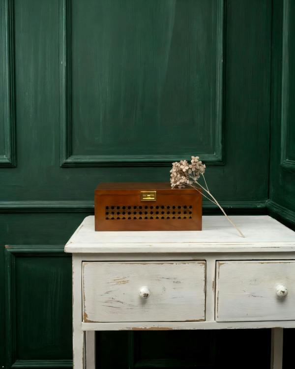 Wooden box with decorative elements on a white table against a green paneled wall