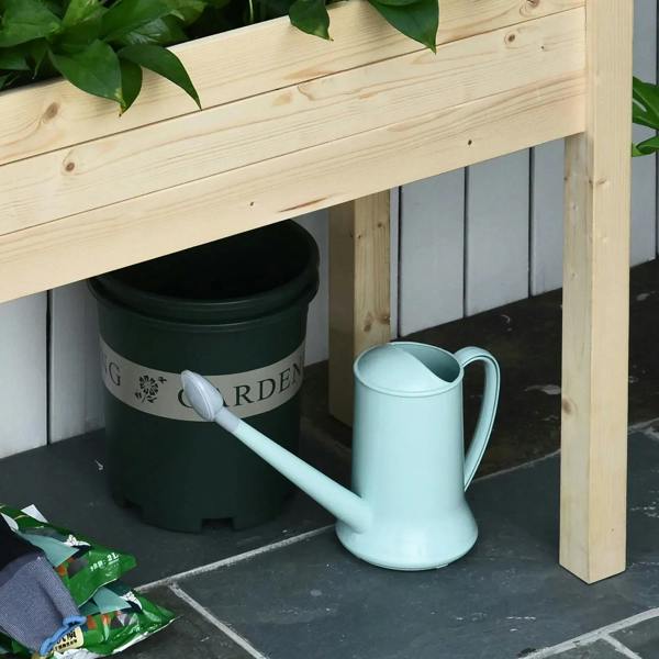 Wooden raised planter base with black liner and garden watering can inside