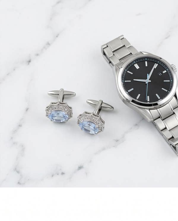 Silver watch and cufflinks with gemstones on a marble surface