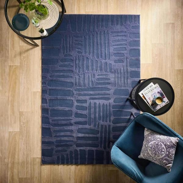 Blue patterned rug on a wooden floor with a blue chair and small table.