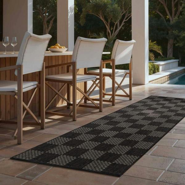 Outdoor patio setting with wooden chairs and a checkered rug.